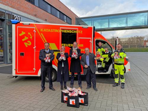 Mehrere Personen mit Stofftieren in der Hand stehen vor einem Rettungswagen der Feuerwehr Hannover.